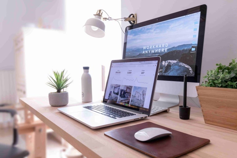 work desk set up with a laptop and monitor, open on a website