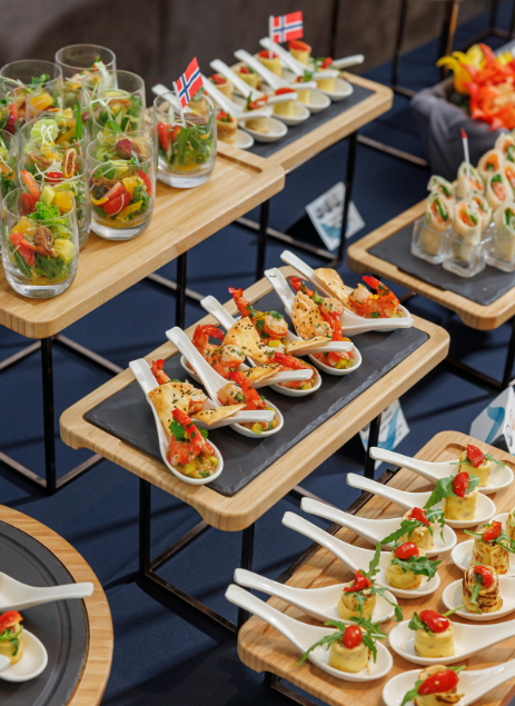 Assorted gourmet appetizers displayed on multi-level wooden serving trays, featuring shrimp, salads, and finger foods