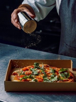 maggi truffle seasoning being sprinkled on pizza